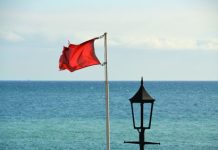 A lanta bandera cora pa alerta comunidad di olanan bruto na Eagle Beach